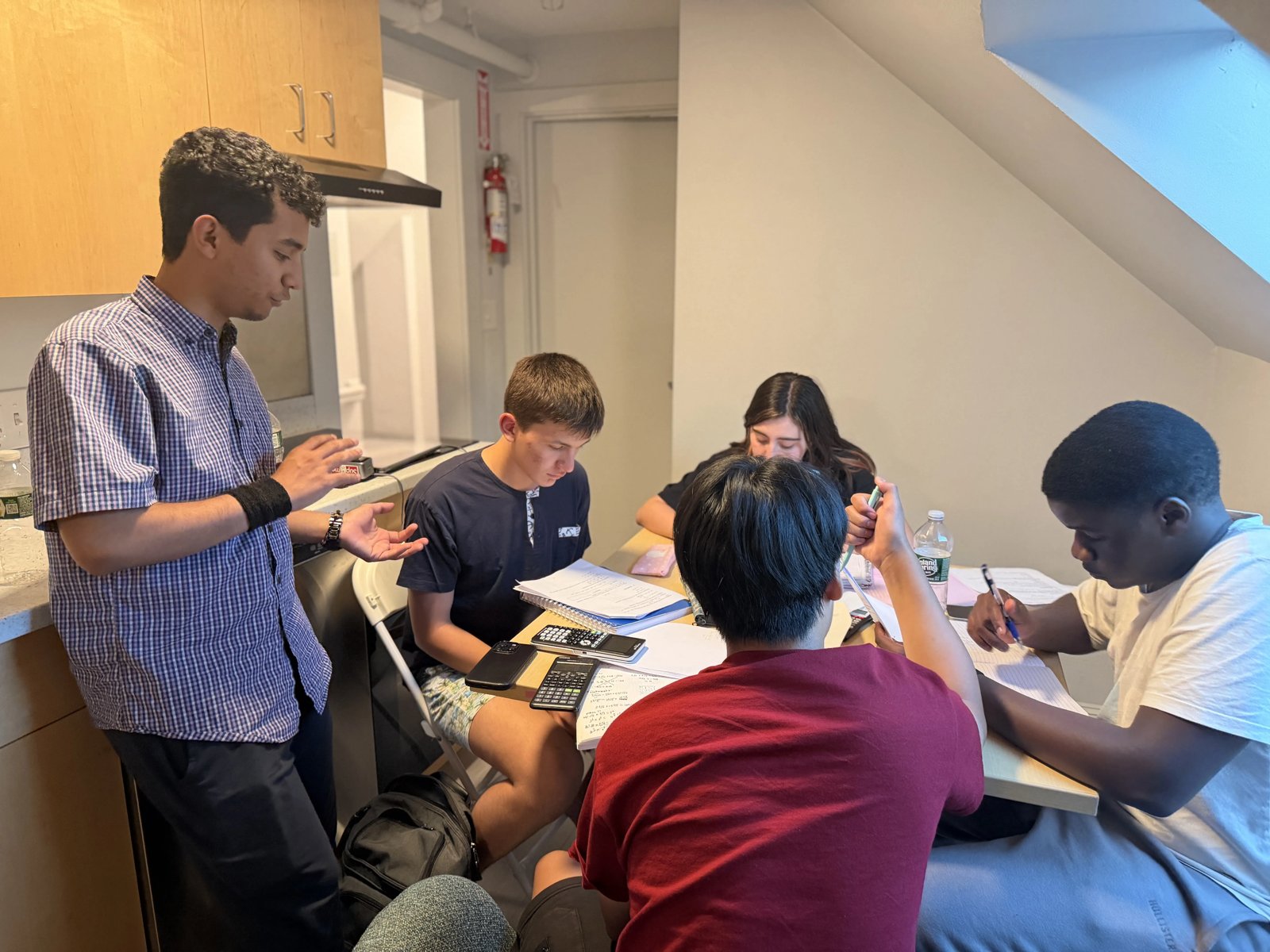 A CyberMath instructor talks a small group of students through problems as they work in their notebooks with calculators