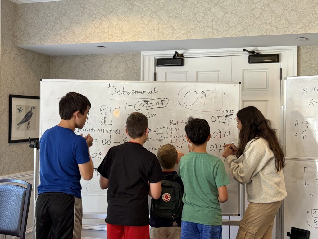 CyberMath students work together at a whiteboard covered in determinant calculations and a proof that 0.999… equals 1